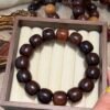 Oversized dark brown 18–19mm barrel-shaped Bodhi bracelet displayed in a wooden jewelry tray.