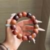 Oversized dark brown 18–19mm barrel-shaped Bodhi bracelet held in one hand.