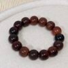 Oversized dark brown 18–19mm barrel-shaped Bodhi bracelet laid flat on light linen.