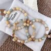 Pistachio, cream, and caramel rounded-cube Bodhi bracelets arranged on soft fabric.