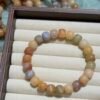 Peach, blush, cream, and beige 12mm twist-cube Bodhi bracelet displayed in a wooden jewelry tray.